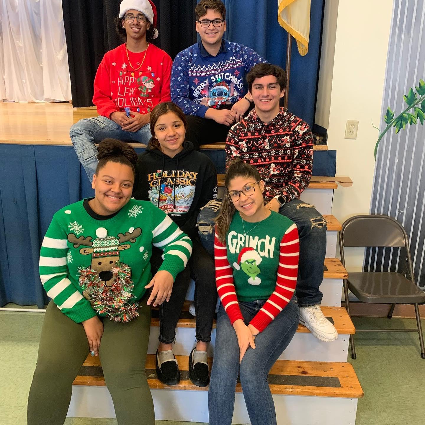 a group of kids wearing ugly sweaters by the steps of the stage